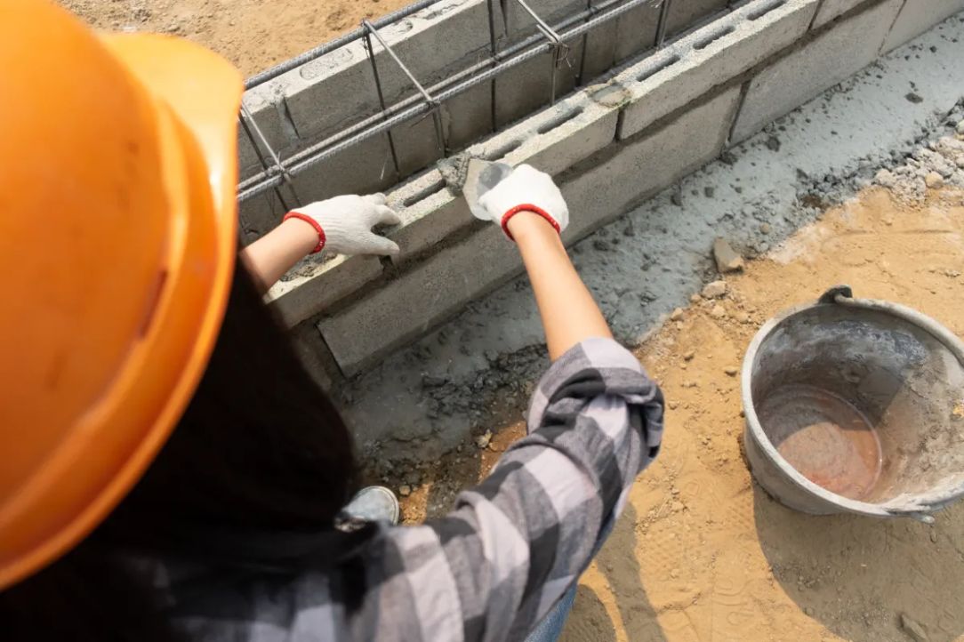 Construction worker laying a concrete block wall on a jobsite